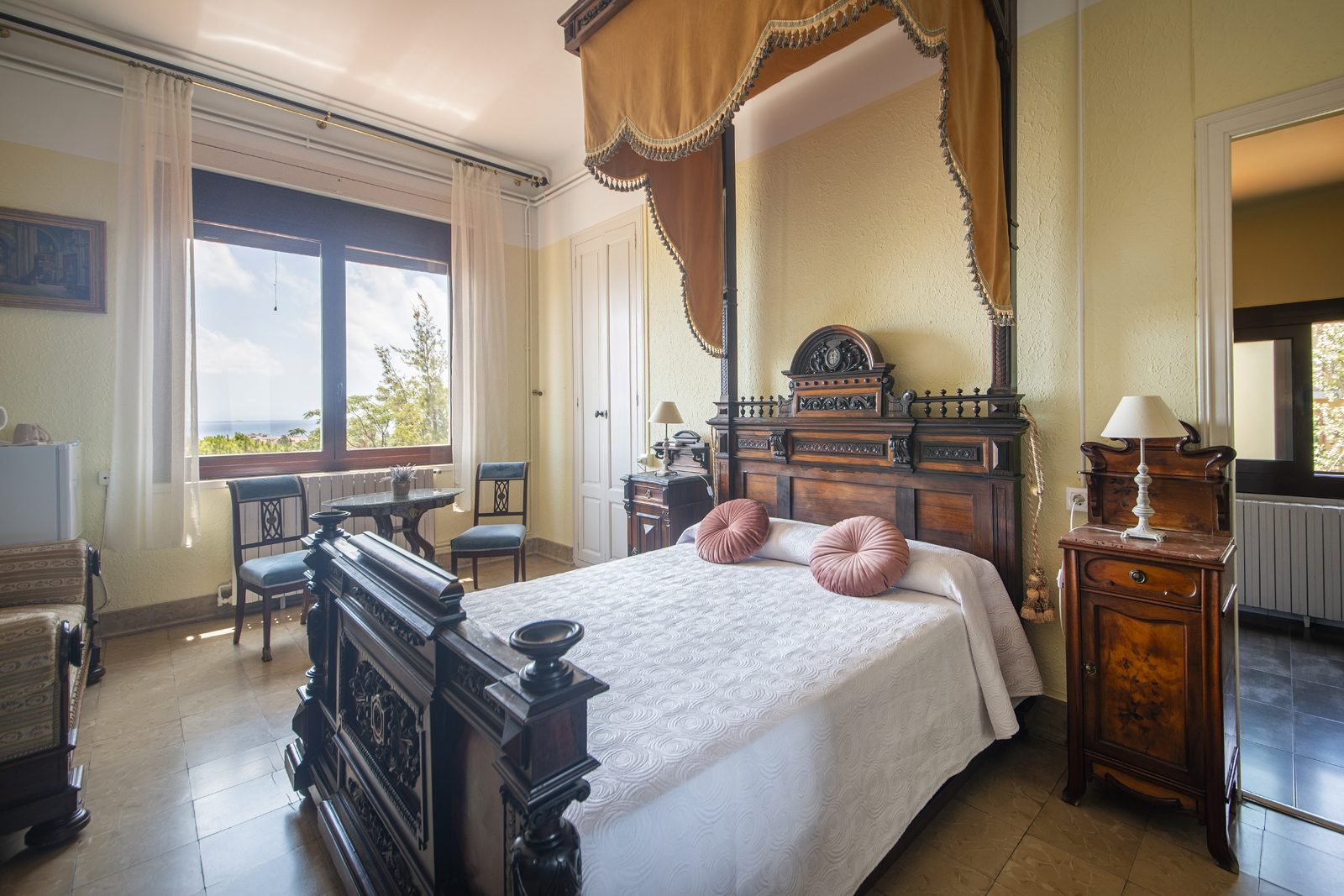 La cama de época bajo el dosel, junto a la ventana