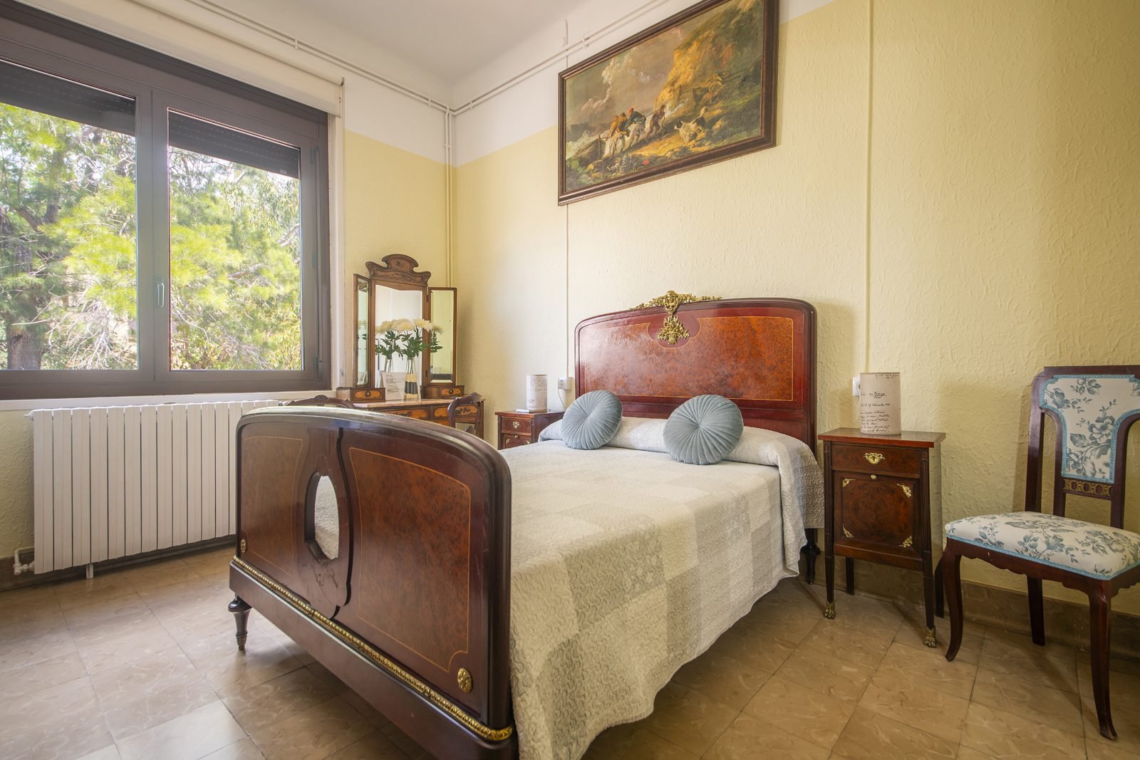 La cama de madera curvada, con la ventana al jardín