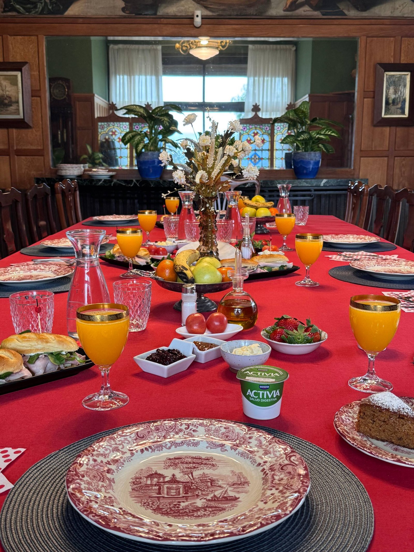 La mesa del desayuno puesta, con zumo, fruta, bizcocho y vajilla antigua